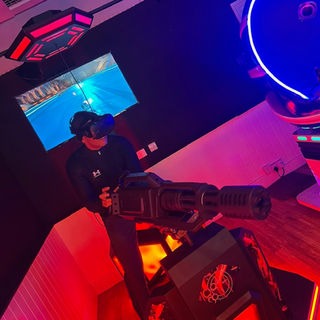 Guest playing the VR Gatling attraction under red neon